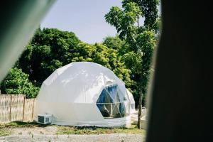 a white dome tent in front of a fence at Tranquil Retreat Dome Glamping with Hotspring Dipping pool - Breathtaking View in Lubo