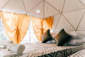 Habitación con cama con almohadas y cortinas. en Tranquil Retreat Dome Glamping with Hotspring Dipping pool - Breathtaking View, en Lubo