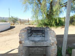 a stone fireplace with a bench in a field at De Rusty Farm in De Rust