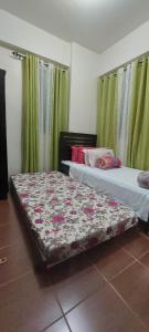 two beds in a room with green curtains at Rochester Condo in Manila
