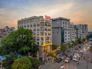 een straat met verkeer en een wit gebouw bij Reyna Luxury Hotel in Hanoi