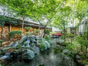 a waterfall in a garden with rocks and trees at Japanese Onsen Ryokan Kohakuen in Fuefuki