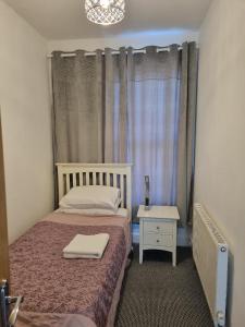 a bedroom with a bed and a nightstand and a window at Cheerful 4 bedroom close to Uclan, Preston City Center in Preston