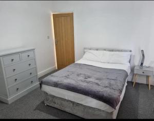 a bedroom with a large bed and a dresser at Cheerful 4 bedroom close to Uclan, Preston City Center in Preston