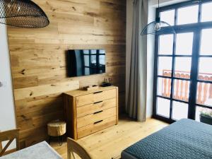 1 dormitorio con pared de madera, TV y vestidor en Strunzova Pila - apartmány s wellness 2,06 a 3,03, en Kvilda