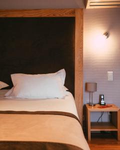 cama con cabecero negro y mesa con lámpara en The Originals Boutique, Hôtel du Pont Roupt, Mende (Inter-Hotel) en Mende