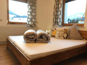 een bed met twee handdoeken en twee ramen bij Haus BIENENHOAMAT in Nauders