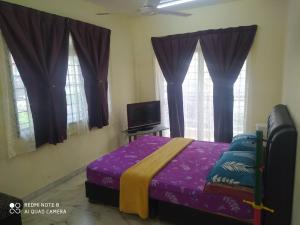 a bedroom with a bed with purple sheets and windows at PD Laguna Homestay Blue & Purple in Port Dickson +110 photos