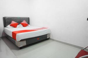 Un dormitorio con una cama con almohadas rojas y blancas. en Hotel O Pondok Cahaya, en Makassar