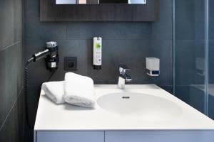 uma casa de banho com um lavatório branco com toalhas em ING Hotel by WMM Hotels em Ingolstadt
