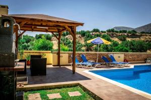 een zwembad met stoelen en een parasol naast een zwembad bij Nine Muses Villas - Clio Terpischori in Chersonissos