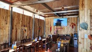 a dining room with wooden walls and tables and chairs at Vừng Homestay - Taxua in Bắc Yên