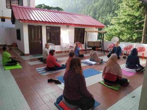 a group of people sitting in a yoga pose in front of a house at HOTEL MANISHA in Gangotri