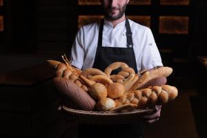 un homme tenant un panier de pain et de viennoiseries dans l'établissement Marco Polo Hotel Gudauri, à Goudaouri