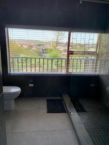 a bathroom with a toilet and a large window at Kindred Spirit Guest Suites with solar power in Knysna