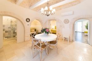 une salle à manger avec une table et des chaises blanches dans l'établissement Trullo Melograno - Dimore nel Tempo, à Alberobello