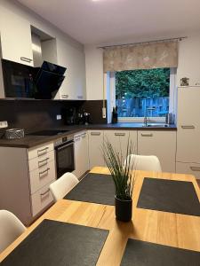 eine Küche mit einem Holztisch mit Stühlen und einem Fenster in der Unterkunft Ferienhaus Segelbär in Hooksiel