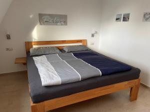 ein Bett mit einem Holzrahmen und blauer und weißer Bettwäsche in der Unterkunft Ferienhaus Segelbär in Hooksiel