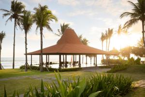 a gazebo on the beach with palm trees at Amarta Beach Retreat by Nakula in Tabanan
