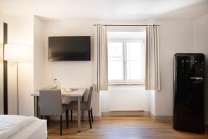 a room with a table and a television and a bedroom at MO Hotel by WMM Hotels in Ingolstadt