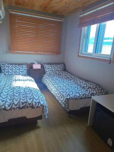 a bedroom with two beds and a television in it at Leehakjang guesthouse in Mokpo