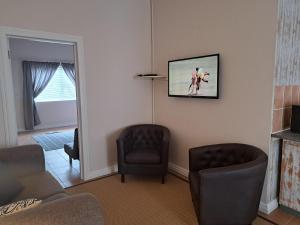 uma sala de estar com duas cadeiras e uma foto na parede em Deri's Lane em Lorraine