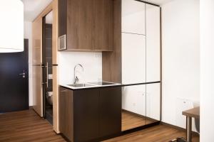 a kitchen with black and white cabinets and a sink at MO Hotel by WMM Hotels in Ingolstadt