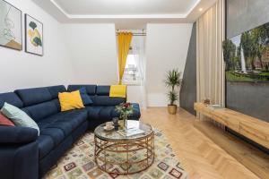 Design 1BDR Loft near Kvaternik Square في زغرب: غرفة معيشة مع أريكة زرقاء وطاولة زجاجية