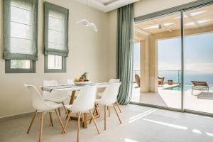 Un comedor con una mesa y sillas blancas. en Villa Sorian Prasino, en Vlachata
