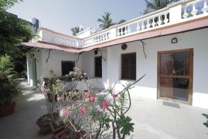 a white house with flowers in the courtyard at Dumas Guest House in Puducherry