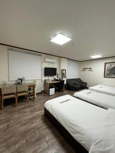 um quarto de hotel com duas camas e um ecrã de projecção em Ekonomy Hotel em Mokpo