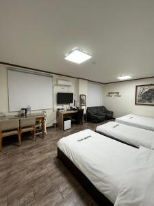 een hotelkamer met 2 bedden en een projectiescherm bij Ekonomy Hotel in Mokpo