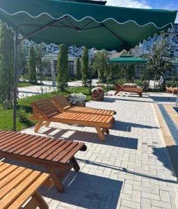 a group of benches sitting under a green umbrella at ЦО Novel Иссык-Куль in Korumdy