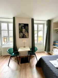 1 dormitorio con 2 sillas, mesa y 2 ventanas en Hôtel Patricia - Strasbourg Hyper Centre, en Estrasburgo