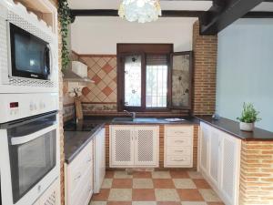 a kitchen with white cabinets and a tv on the wall at Relax, vistas, barbacoa y piscina, junto a Ronda in Arriate