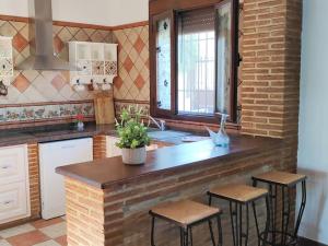 a kitchen with a counter with stools and a sink at Relax, vistas, barbacoa y piscina, junto a Ronda in Arriate +8 photos