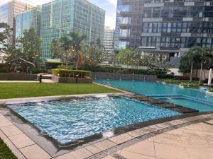 a large swimming pool in a city with tall buildings at Uptown Parksuites II in Manila
