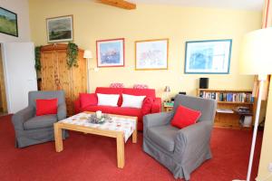 オストゼーバート・ゼリンにあるSeepark Sellin - Haus Baabe - FeWo 432のリビングルーム(赤いソファ、椅子2脚、テーブル付)
