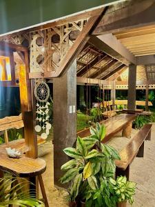 a patio with wooden benches and tables and plants at Isola del Sole Villas and Resort in General Luna