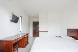 um quarto com 2 camas, uma secretária e uma televisão em Indopurejoy House - Komala Indah Cottages em Kuta