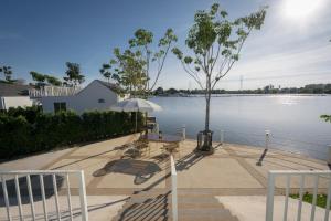 un patio con mesas y una sombrilla junto al agua en Saksiam Lakeside Resort SHA PLUS Certificate, en Nonthaburi