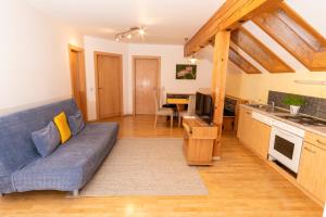 a living room with a blue couch and a kitchen at Landhaus Rainer in Mallnitz