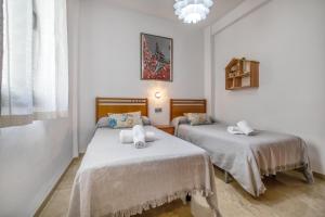 2 Betten in einem Zimmer mit weißen Wänden in der Unterkunft Fleming, cómodo apartamento junto Mezquita y Judería in Córdoba