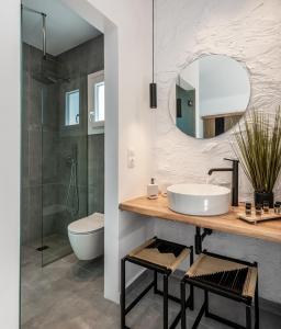 La salle de bains est pourvue d'un lavabo, de toilettes et d'un miroir. dans l'établissement Magma Milos Studios II, à Adamas