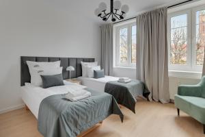 a bedroom with two beds and a chair and windows at Downtown Apartments Old Town Ogarna IV in Gdańsk