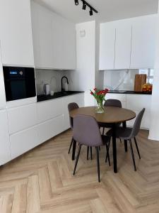 a kitchen with a table and chairs and white cabinets at Casa Baltico Letnica in Gdańsk