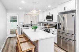 a kitchen with white cabinets and a stainless steel refrigerator at Beautiful Home North Shore Paradise Steps to Beach Unit A in Hauula