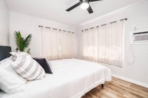 a white bedroom with a bed and a ceiling fan at Beautiful Home North Shore Paradise Steps to Beach Unit A in Hauula