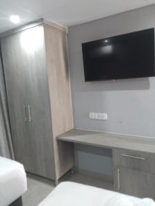 Habitación con escritorio y TV en la pared. en Khayalami Hotel - Emalahleni, en Witbank