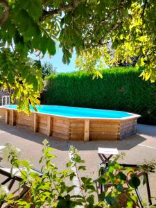 a wooden bench with a pool in front of a hedge at O 4 SAISONS DE BREILBON in Germond